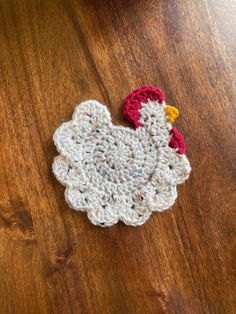 a crocheted chicken sitting on top of a wooden table