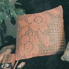 two knitted pillows sitting on top of a couch next to a potted plant