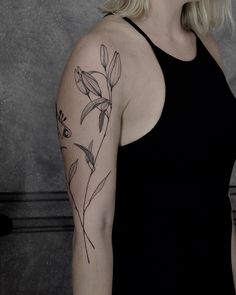 a woman with a flower tattoo on her left arm and right arm behind her head