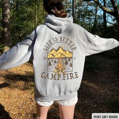 "This cozy \"Life Is Better By The Campfire\" hoodie is the perfect outfit for any camping crew or outdoorsy traveler who loves to explore nature and go on adventures. This camping hoodie features a stylish design with a campfire graphic, making it an ideal gift for any camp lover. Whether you're sitting by the fire with friends or embarking on a new outdoor adventure, this hoodie will remind you that life is always better by the campfire. ✧ SIZING ✧ ⋒ Please check our size chart before placing Cozy Hoodie Sweater For Outdoors, Family Camping Shirts, Camping Fits, Camp Hoodie, Winter Camping Hooded Sweatshirt, Campfire Sweatshirt, Campfire Hoodie, Jacket Aesthetic, Camping Hoodie