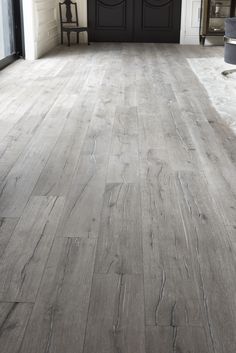 a large white wood floor in a house with black door and chair next to it