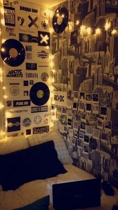 a bed with lots of records on the wall and lights hanging from it's headboard