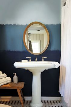 a white pedestal sink sitting under a round mirror