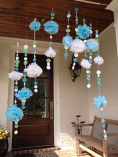 some blue and white paper flowers hanging from the ceiling above a porch door with a bench in front of it