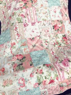 an old quilt is laying on top of a bed with pink and blue flowers all over it