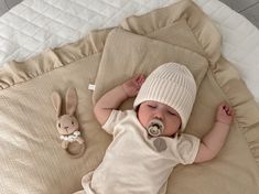 a baby laying on top of a bed with a pacifier in it's mouth