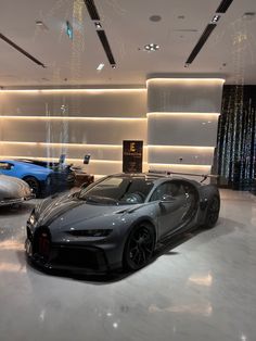 two cars in a showroom with lights on the ceiling and white marble flooring