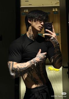 a man with tattoos taking a selfie in the mirror