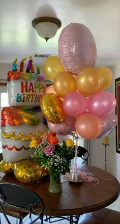 a table topped with lots of balloons next to a cake on top of a wooden table