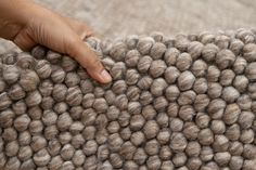 a person's hand touching the top of a rug