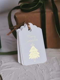 a white christmas gift tag sitting next to a brown box