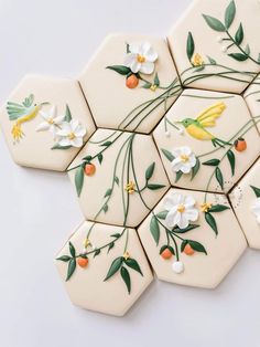 some white tiles with flowers and leaves painted on the backs of them are arranged in hexagonal shapes