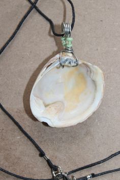 a necklace with a white shell on a black cord