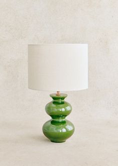 a green lamp sitting on top of a table next to a white lampshade