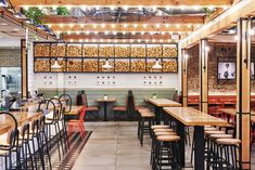 the interior of a restaurant with wooden tables and stools, hanging lights and plants on the wall