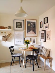 a dining room table with chairs and pictures on the wall above it, along with a bench