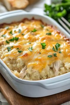 a casserole dish with chicken and cheese in it on a wooden cutting board