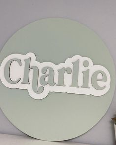 the name charlie is cut out of white paper and placed on a green circle wall