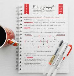 a cup of coffee and two pens on top of a paper with the word management written in it