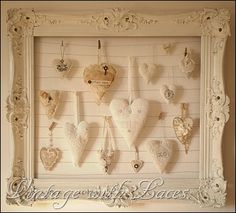 a white frame with many heart shaped ornaments hanging from it's sides on the wall