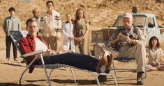 a group of people standing and sitting in the desert