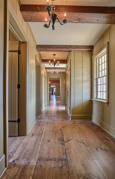 an empty hallway with wood flooring and ceiling lights on either side of the hall