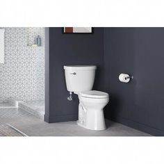 a white toilet sitting in a bathroom next to a walk in shower and tiled walls