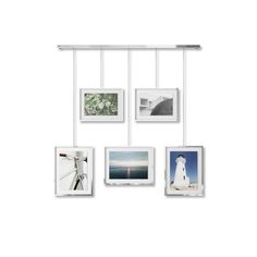 four different pictures hanging on a white wall with metal bars and clips to hang them