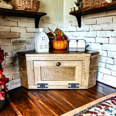 a wooden cabinet sitting on top of a hard wood floor next to a brick wall