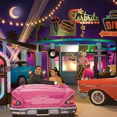 a man and woman posing in front of an old fashioned car at a showroom