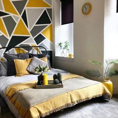 a bed with yellow and gray decor in a bedroom next to a large wall clock