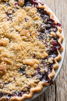 a pie with blueberries and crumbs on it sitting on top of a wooden table