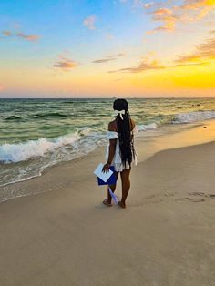 a woman standing on top of a sandy beach next to the ocean