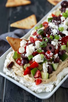 a platter filled with hummus, olives, tomatoes and feta cheese