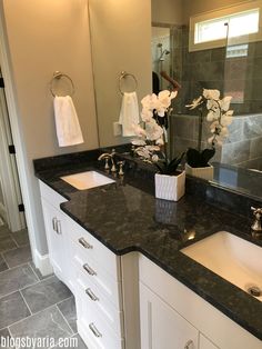 a bathroom with double sinks and marble counter tops