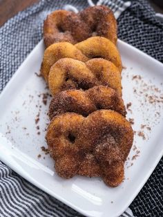 three donuts on a white plate with powdered sugar and brown sugar sprinkles