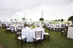 tables and chairs are set up in a tent for an outdoor wedding reception with white linens