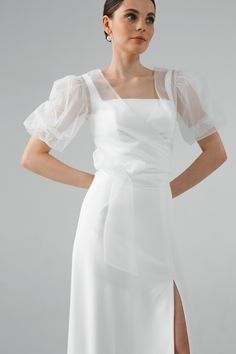 a woman wearing a white dress with sheer sleeves