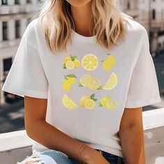 Add a Splash of Citrus Charm with Our Cute Lemon T-Shirt! Squeeze some sunshine into your wardrobe with our delightful lemon-themed t-shirt. Perfect for those who love a pop of cheerful color and a touch of whimsy, this tee is as refreshing as a cool glass of lemonade on a summer day. Why You'll Love It: 🍋 Zesty Design: Featuring a vibrant lemon print that radiates positivity and zest for life, this t-shirt adds a playful twist to your everyday style. 🌿 Soft & Comfortable: Made from 100% cotton, it's not just cute but also ultra-soft and breathable, ensuring all-day comfort wherever your adventures take you. 🎨 Versatile & Fun: Pair it with jeans, shorts, or a cute skirt - this tee effortlessly brightens up any outfit, making it a go-to choice for casual outings and laid-back days. Key F White Summer Tops With Lemon Print, Summer Short Sleeve Top With Lemon Print, White Summer Top With Lemon Print, White Short Sleeve Top With Lemon Print, Yellow Crew Neck Top With Lemon Print, White Lemon Print Summer Top, Cotton Graphic Tee With Lemon Print, Yellow T-shirt With Lemon Print For Spring, White T-shirt With Lemon Print For Summer