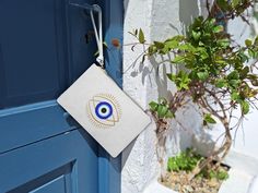 Elevate your summer style with our White Clutch Bag featuring a captivating evil eye (nazar) design, blending the timeless allure of Greek culture with modern elegance. This chic accessory embodies the serene, sun-soaked charm of the Greek islands, making it the perfect handbag for those unforgettable summer evenings in Santorini, Mykonos, or the bustling streets of Athens. With its sleek white base and striking evil eye pattern, this clutch embodies both simplicity and sophistication, offering a look that's effortlessly stylish. Inspired by the essence of a Greek summer, this white clutch exudes a sense of relaxed luxury that pairs beautifully with any outfit, from a flowing sundress to a tailored evening ensemble. Its clean white color complements the intricate blue evil eye, a symbol of White Rectangular Pouch For Daily Use, White Travel Clutch Pouch, Rectangular White Pouch For Daily Use, Handmade White Pouch Clutch, White Clutch Bag As Gift, Handmade White Clutch Pouch, White Clutch Bag For Gifts, White Clutch Bag For Gift, White Bags With Zipper Pouch For Gifts