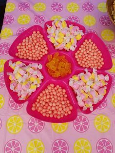 a pink plate topped with lots of candy on top of a purple table cloth covered in lemon slices