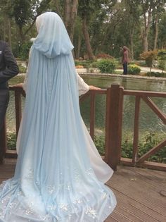 a man and woman standing on a bridge looking at the water