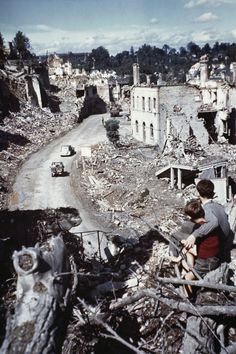 two boys sitting on the rubble of a destroyed building looking at something in the distance