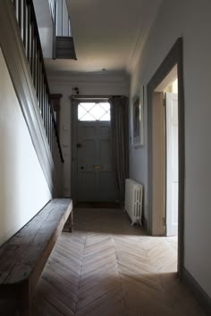 an empty hallway with a wooden bench and stairs