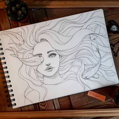 a drawing of a woman's face on top of a wooden table next to other items