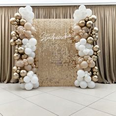 a gold and white balloon arch with balloons