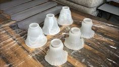 several white vases sitting on top of a wooden table