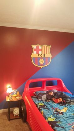 a child's bedroom with a soccer themed bed and wall decal in the background