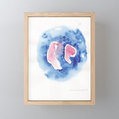 a watercolor painting with pink and blue shapes on the bottom, in a wooden frame