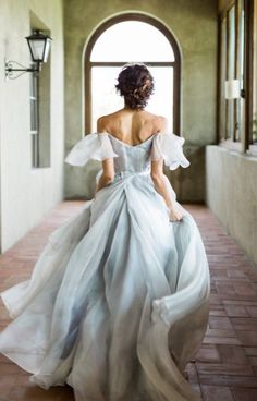 a woman in a white dress is walking down the hall with her back to the camera